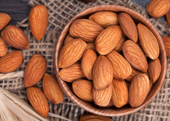 Almonds superfood in a wooden dish on vintage textile background