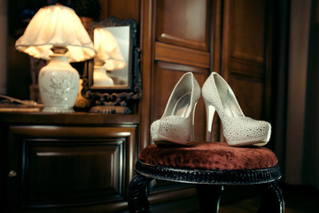 Pair of white luxury shoes for bride in beautiful interior room.