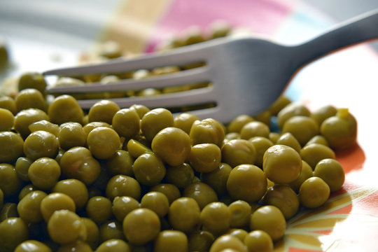 Arvejas en un plato con tenedor.