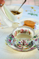 Pouring milk into vintage bone china cup. Concept of Mother's Day. 