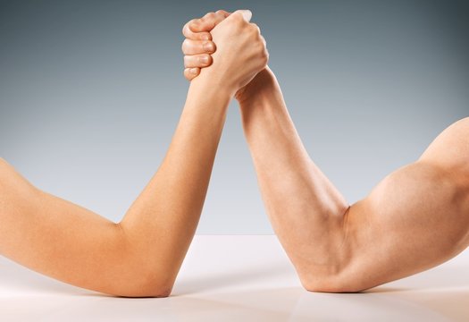 Adult. A man and woman with hands clasped arm wrestling