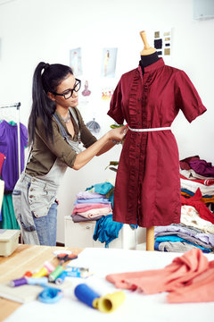 Young female designer measuring dress