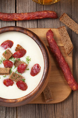 Beer cream white soup with sausages on vintage background