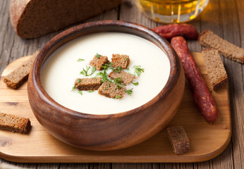 Traditional beer cream soup with dill croutons and sausage in wo