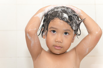 Cute asian girl is washing her hair in bath. The symbol of purit