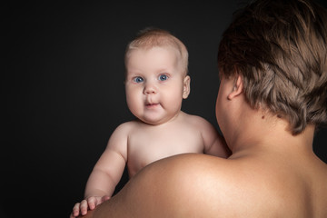 Cute baby looking over father's shoulder .