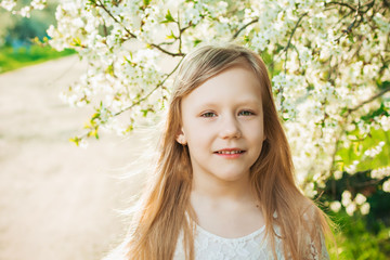 Little girl in a white dress on a sunny spring garden