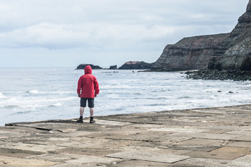 Man in red rain jacket cagoule on Whitby Harbour