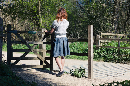 Woman standing by gate in forest