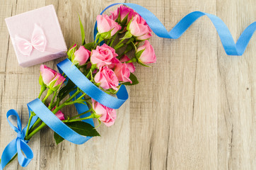 Empty wooden background with colorful flowers and blue ribbon