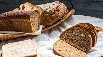Assorted bread slices in a basket on a white linen tablecloth