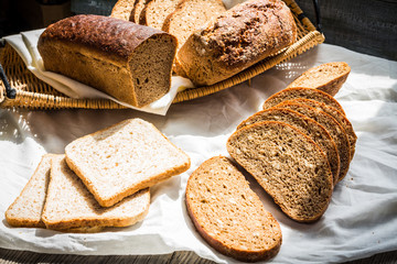 Assorted bread slices in a basket on a white linen tablecloth