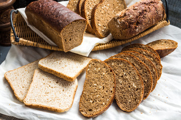 Assorted bread slices in a basket on a white linen tablecloth