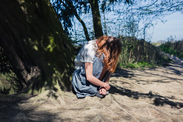 Naklejka premium Young woman sitting under tree by the water