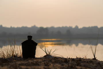 Army water canteen at river on sunset background