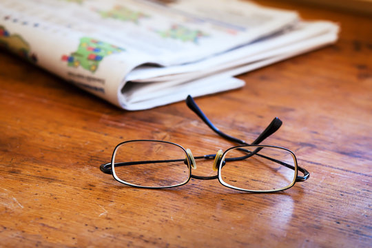 reading newspapers, close up of glasses on the wooden table