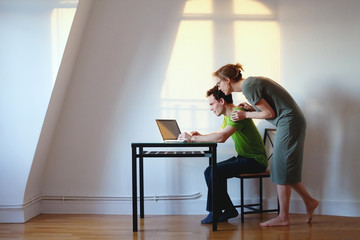young couple looking at the laptop at their home in bright interior