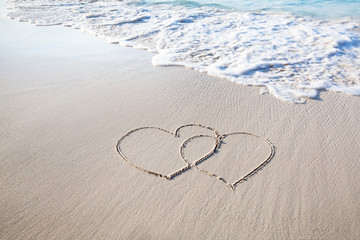 two hearts drawn on perfectly white sand of paradise beach - obrazy, fototapety, plakaty
