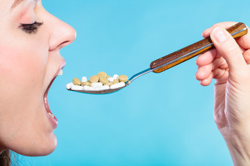 Young woman eating pills on a spoon