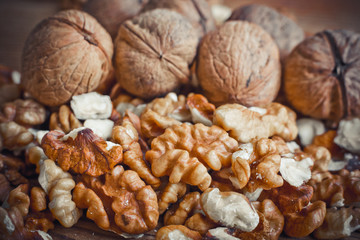 Walnut kernels and whole walnuts wood background