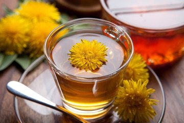 Kräutertee aus Löwenzahn mit gelben Blüten auf Holztisch