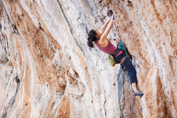 Young female rock climber on overhanging cliff