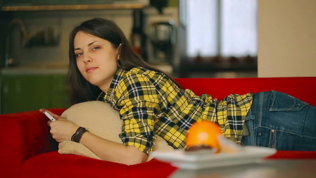 Happy girl lying and texting on smartphone, steadycam shot
