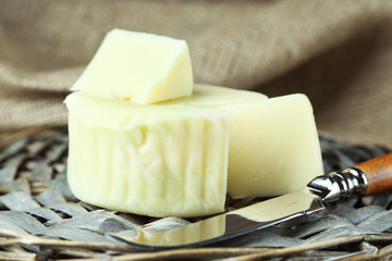 Cheese on wicker tray and sackcloth, closeup
