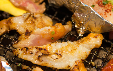 Korean style grilled meat and fish closeup on hot grid