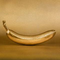 Whole golden banana on gold background
