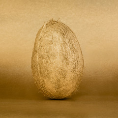Whole golden coconut on gold background