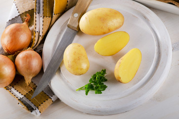 Naklejka na ściany i meble Fresh potatoes on a white cutting board