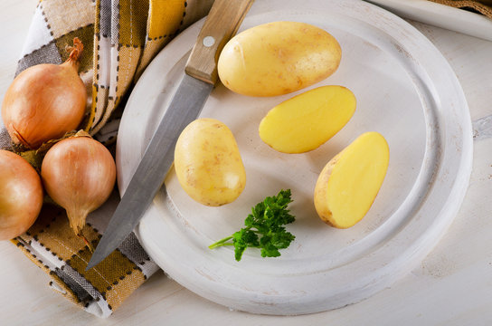 Fresh potatoes on a white cutting board
