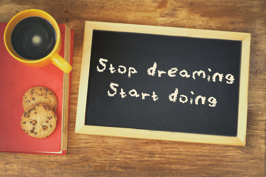 top view image of blackboard with the phrase stop dreaming start