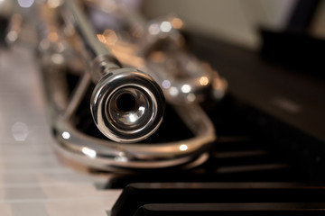 Fototapeta premium Trumpet segment closeup lying on piano keys