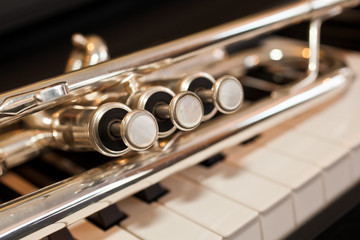 Naklejka premium Trumpet segment closeup lying on piano keys
