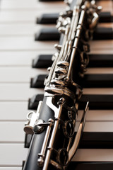 Fragment of a clarinet lying on piano keys - obrazy, fototapety, plakaty