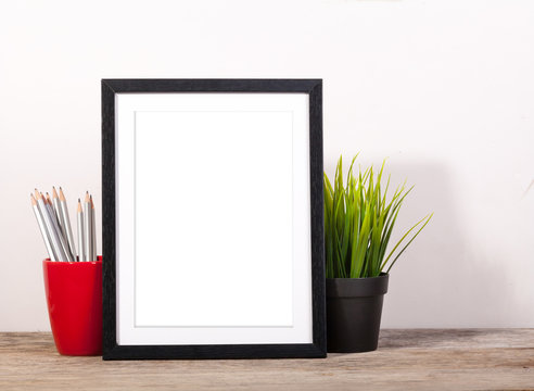 picture frame with office items and pot planr on wooden table