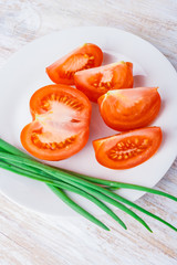 sliced tomato and chives on a white plate