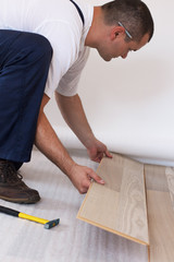 Fototapeta na wymiar Man laying laminate flooring in a home.