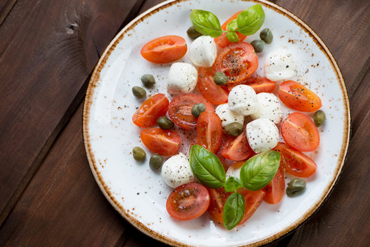 Caprese salad with caper berries, view from above, studio shot