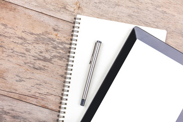 Tablet and notepad on a wooden desktop