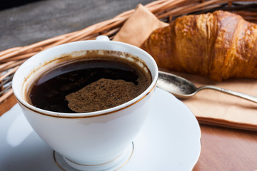 A cup of coffee and a croissant. breakfast table