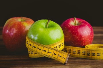 Green and red apples with measuring tape