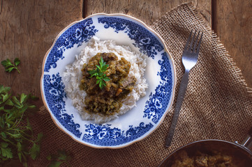 Risotto with mushroom and broccoli, decorated with parsley, on wooden table