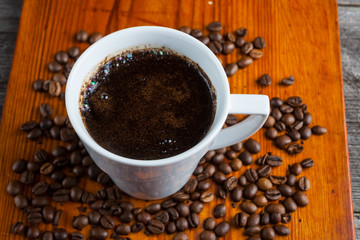 Coffee beans and cup of coffee on wooden table
