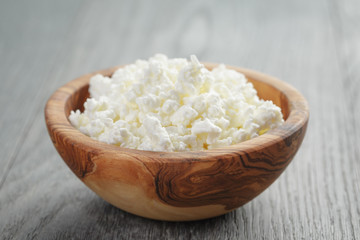 fresh cottage cheese in a wood bowl on a wooden table