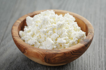 fresh cottage cheese in a wood bowl on a wooden table