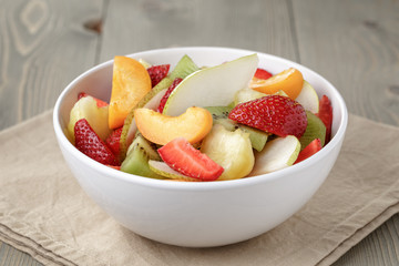 fresh mix fruit salad with strawberry, kiwi and peach, on table