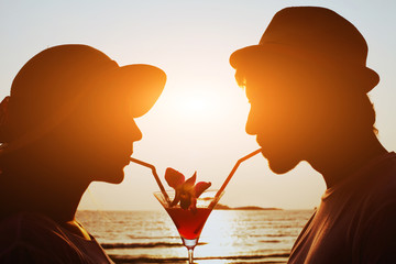 party time, couple drinking cocktail together on the beach during their honeymoon